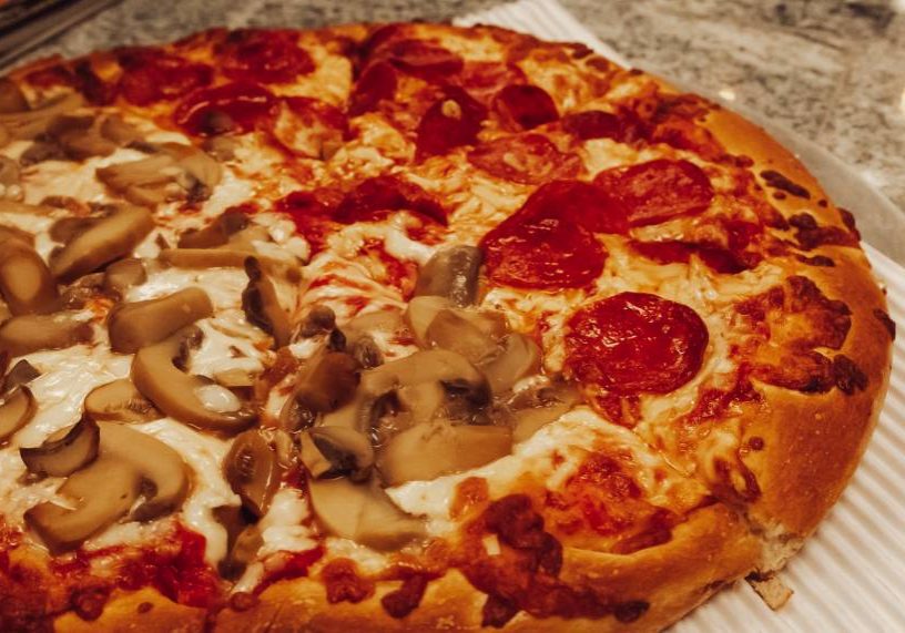 A pizza with mushrooms and pepperoni on a plate.